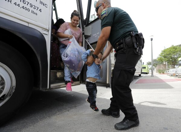 
              A transport officer, right, helps immigrants Dilma Araceley Riveria Hernandez, and her son, Anderson Alvarado, 2, get off the bus after they were processed and released by U.S. Customs and Border Protection, Sunday, June 24, 2018, in McAllen, Texas. (AP Photo/David J. Phillip)
            