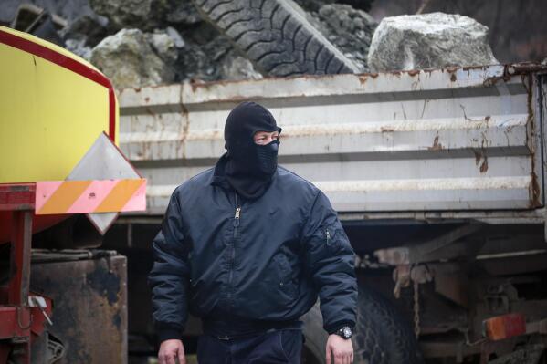 A masked Serb looks on as they remove trucks from Rudare barricade near the northern, Serb-dominated part of ethnically divided town of Mitrovica, Kosovo, Thursday, Dec. 29, 2022. Serbia on Thursday revoked combat readiness of its troops on the border with Kosovo as local Serbs started removing more than a dozen of the roadblocks they had set up in the north of the state, in a sign of easing of tensions that have sparked fears of a new conflict in the Balkans. (AP Photo/Visar Kryeziu)