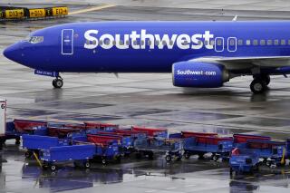 FILE - A Southwest Airlines jet passes unused luggage carts as it arrives, Dec. 28, 2022, at Sky Harbor International Airport in Phoenix. The U.S. Transportation Department said Wednesday, Jan. 25, 2023, it is investigating whether Southwest Airlines deceived customers by knowingly scheduling more flights in late December than it realistically could handle. (AP Photo/Matt York, File)