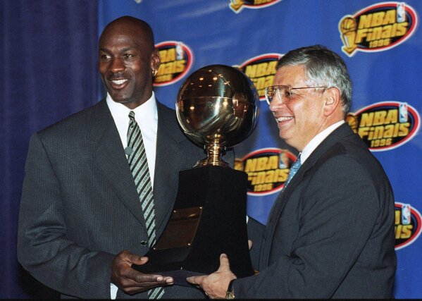 FILE - In this June 18, 1996, file photo, Chicago Bulls' Michael Jordan, left, receives the NBA Finals Most Valuable Player trophy from Commissioner David Stern during a ceremony in Chicago. David Stern, who spent 30 years as the NBA's longest-serving commissioner and oversaw its growth into a global power, has died on New Year’s Day, Wednesday, Jan. 1, 2020. He was 77.  (AP Photo/Charles Bennett, File)