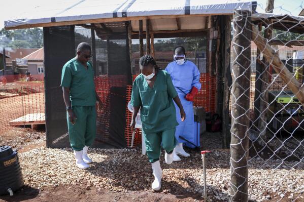 A medical attendant disinfects the rubber boots of a medical officer before leaving the Ebola isolation section of Mubende Regional Referral Hospital, in Mubende, Uganda Thursday, Sept. 29, 2022. In this remote Ugandan community facing its first Ebola outbreak, testing trouble has added to the challenges with symptoms of the Sudan strain of Ebola now circulating being similar to malaria, underscoring the pitfalls health workers face in their response. (AP Photo/Hajarah Nalwadda)