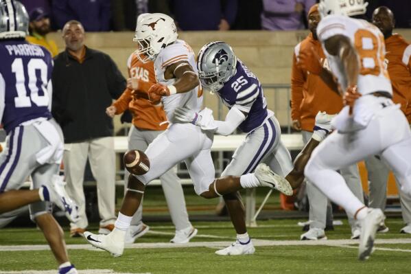 Kansas State cornerback Ekow Boye-Doe (25) knocks the ball out of the hands of Texas running back Roschon Johnson (2), creating a fumble that Kansas State recovered, during the first half of an NCAA college football game Saturday, Nov. 5, 2022, in Manhattan, Kan. (AP Photo/Reed Hoffmann)