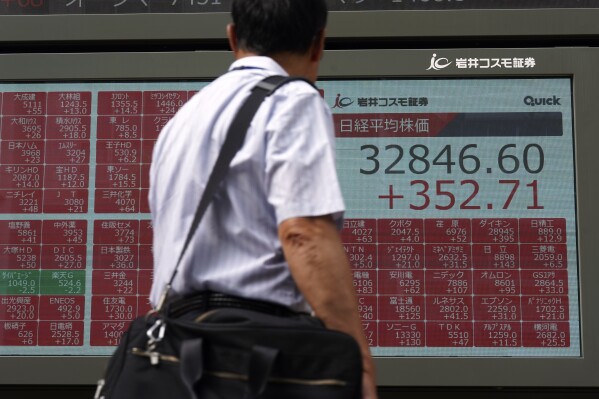 A person looks at an electronic stock board showing Japan's Nikkei 225 index at a securities firm Wednesday, July 19, 2023, in Tokyo. Asian shares are mixed after Wall Street’s frenzy around artificial intelligence helped pushed U.S. stocks to their best level in more than 15 months. (AP Photo/Eugene Hoshiko)