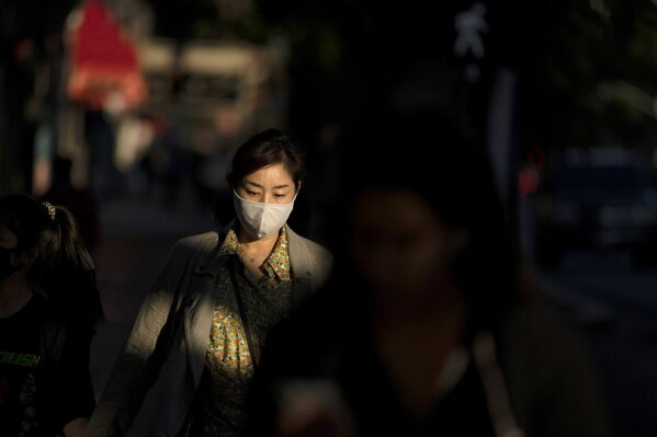 FILE - In this Nov. 12, 2020, file photo, a woman wearing a face mask walks along a street in the Hollywood section of Los Angeles. California Gov. Gavin Newsom is imposing an overnight curfew as the most populous state tries to head off a surge in coronavirus cases. Newsom announced Thursday, Nov. 19, a limited stay-at-home order in 41 counties that account for more than 90 percent of the state's population. Starting Saturday, all non-essential work, movement and gatherings must cease between 10 p.m. and 5 a.m. (AP Photo/Jae C. Hong, File)