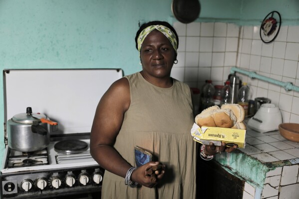 María de los Ángeles Pozo, a retired school worker, poses for a photo in her kitchen with some of the subsidized food she receives through a government ration book known as a “libreta,” in Havana, Cuba, Wednesday, March 6, 2024. Pozo thinks back fondly to when a government ration book fed her family everything from hamburgers, fish and milk to chocolate and beer. (AP Photo/Ariel Ley)
