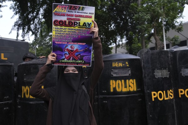 A woman holds a poster during a rally against British band Coldplay ahead of its concert in Jakarta, Indonesia, Wednesday, Nov. 15, 2023. A group of conservative Muslims staged the rally calling for the cancellation of the concert over the band's support for the LGBTQ+ community. (AP Photo/Tatan Syuflana)
