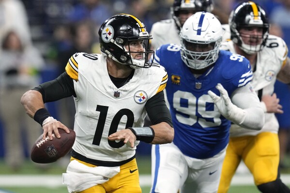 Pittsburgh Steelers quarterback Mitch Trubisky (10) rolls out, looking to pass, with Indianapolis Colts defensive tackle DeForest Buckner (99) in pursuit during the second half of an NFL football game in Indianapolis on Saturday, Dec. 16, 2023. (AP Photo/Darron Cummings)