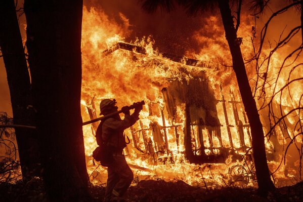 
              FILE - In this Friday, Nov. 9, 2018 file photo, firefighter Jose Corona sprays water as flames from the Camp Fire consume a home in Magalia, Calif. More than 2.7 million Californians live in areas that are at very high risk for wildfires. One in 12 homes in California are at high risk of burning in a wildfire. The more information we can share about where and how we're falling short, the quicker we can come together on potential solutions. (AP Photo/Noah Berger, File)
            