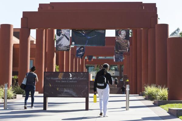 FILE - Students walk past the Harriet and Charles Luckman Fine Arts Complex at the Cal State University, Los Angeles campus on  April 25, 2019. California State University, the country's largest four-year university system, will eliminate SAT and ACT standardized tests from its admission requirements in a move that places California's public universities at the forefront of a national trend to drop the exams. (AP Photo/Damian Dovarganes, File)