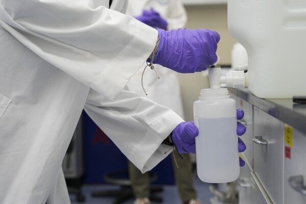Logan Feeney pours a water sample with forever chemicals, known as PFAS, into a container for research, April 10, 2024, at a U.S. Environmental Protection Agency lab in Cincinnati. (AP Photo/Joshua A. Bickel, File)