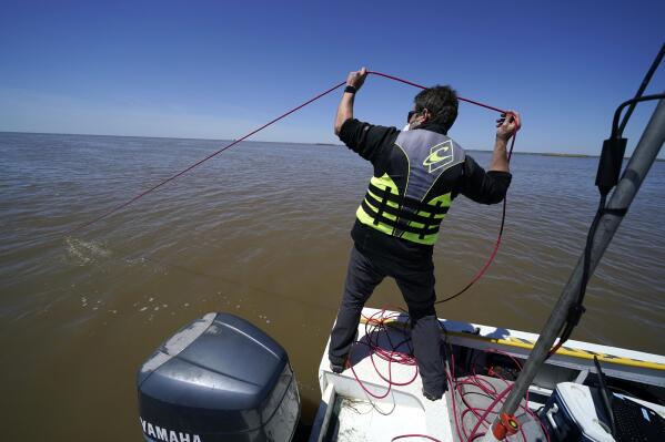 Cedric Fichot, Boston University assistant professor Department of Earth and Environment drops a compact optical profiling system, measuring light and particle density, into the Wax Lake Delta in the Atchafalaya Basin, in St. Mary Parish, La., Friday, April 2, 2021. NASA is using high-tech airborne systems along with boats and mud-slogging work on islands for a $15 million study of these two parts of Louisiana's river delta system. (AP Photo/Gerald Herbert)