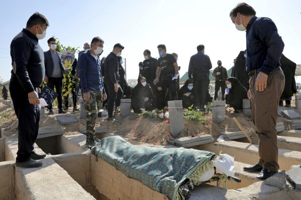 Mourners attend the funeral of a person who died from COVID-19 at the Behesht-e-Zahra cemetery on the outskirts of Tehran, Iran, Sunday, Nov. 1, 2020. The cemetery is struggling to keep up with the coronavirus pandemic ravaging Iran, with double the usual number of bodies arriving each day and grave diggers excavating thousands of new plots. (AP Photo/Ebrahim Noroozi)