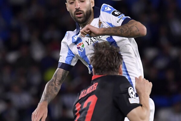 Real Sociedad's Brais Mendez jumps for the ball Salzburg's Andreas Ulmer during a Champions League Group D soccer match between Real Sociedad and Salzburg at the Reala Arena stadium in San Sebastian, Spain, Wednesday, Nov.29, 2023. (AP Photo/Alvaro Barrientos)