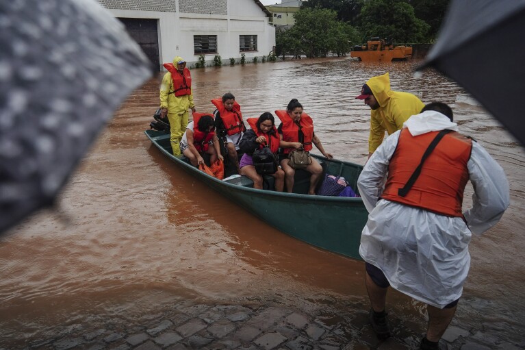 Brandweerlieden evacueren mensen uit een overstroomd gebied na zware regenval in Sao Sebastião do Cai, staat Rio Grande do Sul, Brazilië, donderdag 2 mei 2024. (AP Photo/Carlos Macedo)