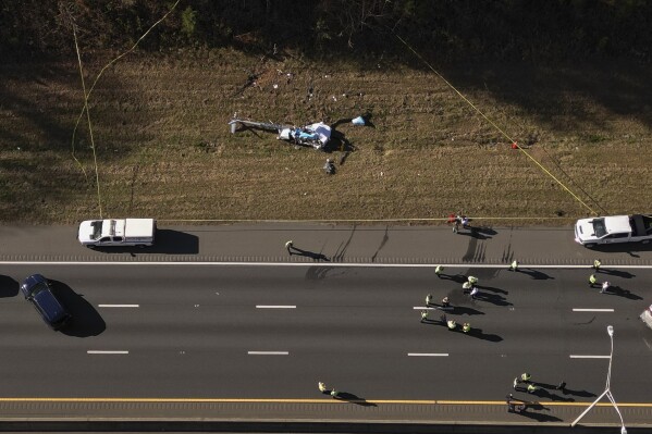 FILE - In this image taken with a drone, emergency personnel work at the scene of a helicopter crash on the side of Interstate 77 South in Charlotte, N.C., Nov. 22, 2022. Investigators found disconnected and missing hardware aboard the helicopter that crashed in 2022, killing the pilot and a North Carolina television station’s meteorologist, according to the National Transportation Safety Board's final report on the crash, which was released Thursday, May 2, 2024. (Alex Slitz/The Charlotte Observer via AP, File)