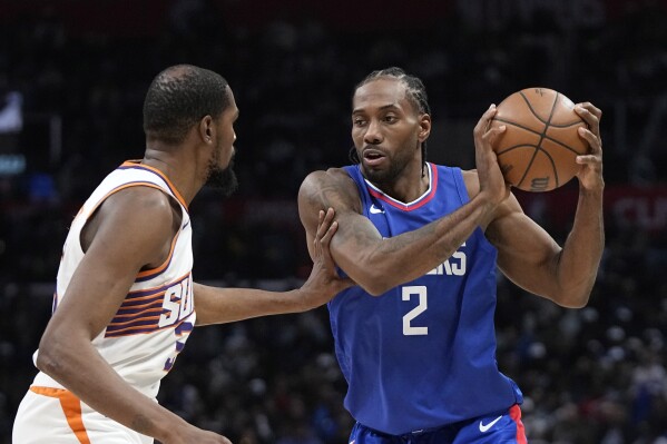 Los Angeles Clippers forward Kawhi Leonard, right, tries to pass as Phoenix Suns forward Kevin Durant defends during the second half of an NBA basketball game Monday, Jan. 8, 2024, in Los Angeles. (AP Photo/Mark J. Terrill)