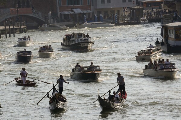 A view of boats and gondolas on a canal, in Venice, Italy, Wednesday, Sept. 13, 2023. The Italian city of Venice has been struggling to manage an onslaught of tourists in the budget travel era. The stakes for the fragile lagoon city are high this week as a UNESCO committee decides whether to insert Venice on its list of endangered sites. (AP Photo/Luca Bruno)