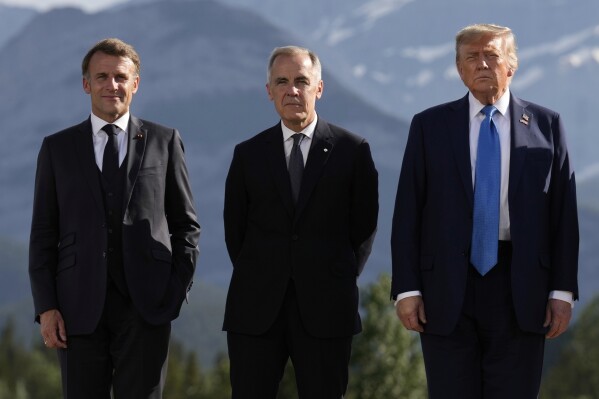 From left, France's President Emmanuel Macron, Canada's Prime Minister Mark Carney and President Donald Trump, pose during a group photo at the G7 Summit, Monday, June 16, 2025, in Kananaskis, Canada. (AP Photo/Mark Schiefelbein)