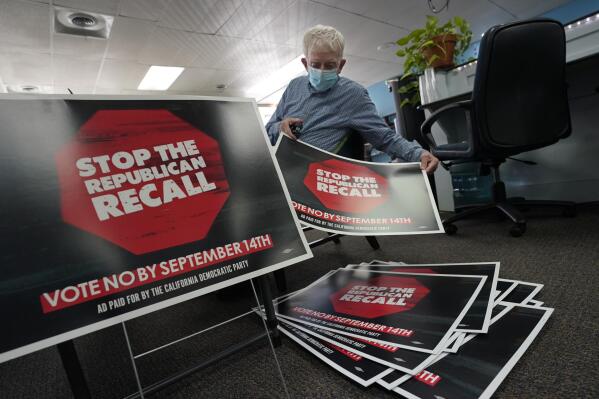FILE - In this July 29, 2021, file photo, volunteer Merle Canfield assembles yard signs against the Sept. 14, recall election of Gov. Gavin Newsom, at the Fresno County Democratic Party headquarters in Fresno, Calif. Democratic state lawmakers Sen. Steve Glazer and Assemblyman Marc Berman called for reforming the recall election requirements, Wednesday Sept. 15, 2021. This could include increasing the number of signatures to force a recall election, raising the standards to require malfeasance on the part of the office-holder and change the current process in which someone with a small percentage of votes could replace a sitting governor. (AP Photo/Rich Pedroncelli, File)