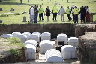FILE - In this Friday, July 30, 2021, photo, a group prays during a small ceremony as remains from a mass grave are reinterred at Oaklawn Cemetery in Tulsa, Okla. Investigators say another step forward has been taken in efforts to identify possible victims of the Tulsa Race Massacre. The committee overseeing the search for mass graves of victims was told Tuesday, June 21, 2022, that enough usable DNA for testing has been found in two of the 14 sets of remains that were removed from Tulsa's Oaklawn Cemetery a year ago. (Mike Simons/Tulsa World via AP, File)