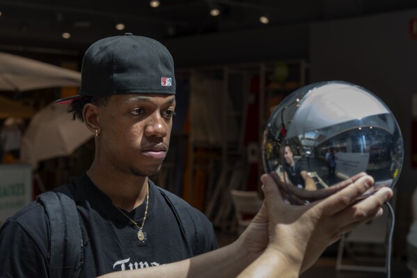 Carlos Jose, 21, has his eyes scanned by an orb, at a Worldcoin registration point in Barcelona, Spain, on Friday, Aug. 4, 2023. Weeks after its international launch, Worldcoin is drawing the attention of privacy regulators around the world. The international ID startup is now having to defend itself in investigations over whether the biometric data that the company is collecting is truly secure. (AP Photo/Emilio Morenatti)