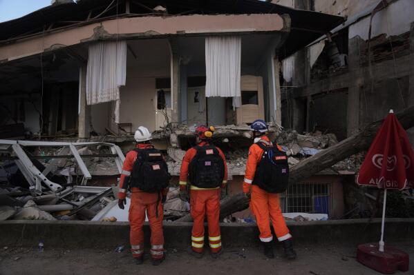 Members of the British rescue team search in a destroyed house in Antakya, southern Turkey, Thursday, Feb. 9, 2023. Tens of thousands of people who lost their homes in a catastrophic earthquake huddled around campfires in the bitter cold and clamored for food and water Thursday, three days after the temblor hit Turkey and Syria. (AP Photo/Khalil Hamra)