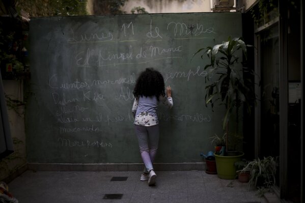 Odara Luna Farmetano uses a wall at her home as a chalkboard during a government-ordered lockdown to curb the spread of the new coronavirus in Buenos Aires, Argentina, Monday, May 11, 2020. (AP Photo/Natacha Pisarenko)