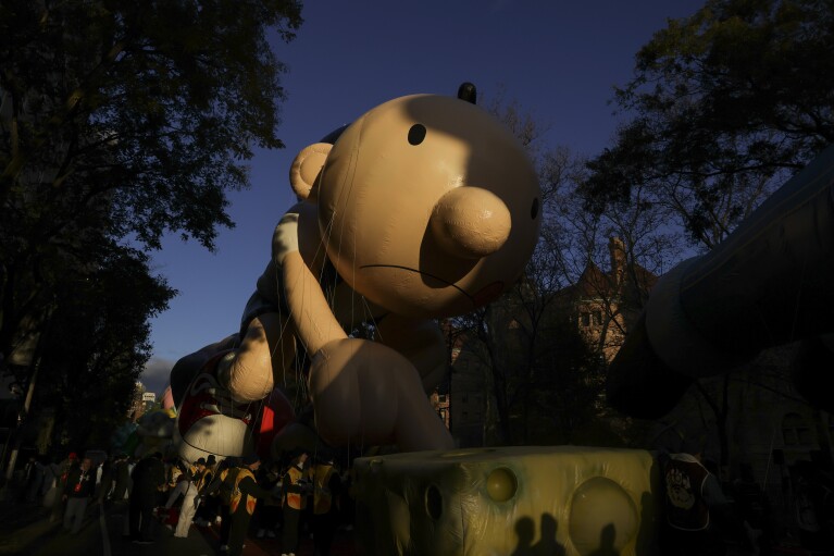 Balloon handlers gather at the base of the Diary of a Wimpy Kid balloon before the start of the Macy's Thanksgiving Day parade, Thursday, Nov. 23, 2023, in New York. (AP Photo/Jeenah Moon)