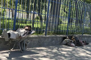 In this May, 6, 2020, photo, beggars sleep on the side of the road in Kabul, Afghanistan, where there have been an increase in the number of beggars during the city lockdown for the coronavirus. (AP Photo/Rahim Faiez)