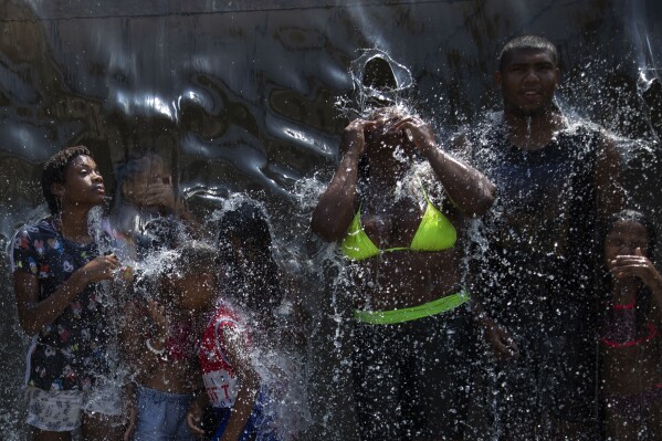 People cool off in a water fountain at Madureira Park amid a heat wave in Rio de Janeiro, Brazil, Wednesday, Nov. 15, 2023. (AP Photo/Bruna Prado)
