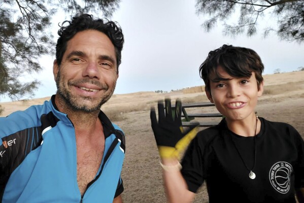 In this image provided courtesy of the family by Abbey Onn, Ofer Kalderon, left, and his son Erez are pictured in this family photo. Abbey Onn lost her aunt and a young cousin when Hamas militants rampaged through Kibbutz Nir Oz on Oct. 7. Now Onn is worried about what will happen to three other family members taken hostage that day, as Israel pounds Gaza City in a bid to end Hamas’ control of the Gaza Strip. She wants the world to remember that Ofer Kalderon, 50, and his children Sahar, 16, and Erez, 12, are caught in the cross-fire. (Courtesy of family via AP)