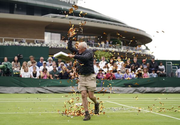 A Just Stop Oil protester on court 18 throwing confetti on to the grass during Britain's Katie Boulter's first-round singles match against Australia's Daria Saville on day three of the Wimbledon tennis championships in London, Wednesday, July 5, 2023. (Adam Davy/PA via AP)
