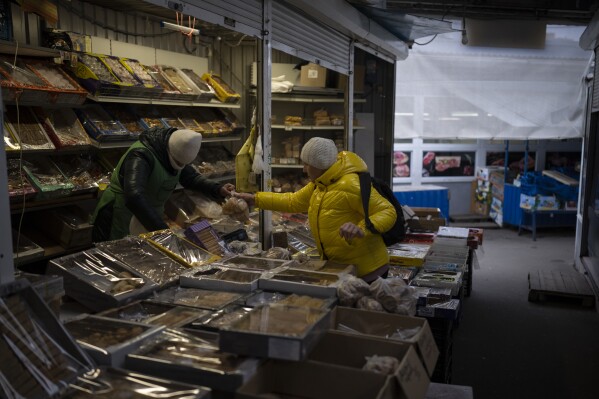 FILE - A woman buys from a vendor at a market in Kyiv, Ukraine, Monday, Jan. 30, 2023. EU leaders on Thursday, Feb. 1, 2024, sealed a deal to provide Ukraine with 50 billion euros ($54 million) to shore up its economy ravaged by a nearly two-year-old war with Russia. (AP Photo/Daniel Cole, File)