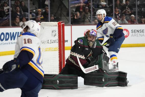 Arizona Coyotes goaltender Karel Vejmelka, middle, makes a save on a shot by St. Louis Blues center Robert Thomas (18) as Blues center Jordan Kyrou (25) looks on during the second period of an NHL hockey game Tuesday, March 7, 2023, in Tempe, Ariz. (AP Photo/Ross D. Franklin)
