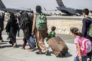 FILE - In this Aug. 24, 2021, file photo, provided by the U.S. Marine Corps, families walk towards their flight during ongoing evacuations at Hamid Karzai International Airport, in Kabul, Afghanistan. A school district in a San Diego suburb that is home to a large refugee population says many of its families who had taken summer trips to Afghanistan to see their relatives have gotten stuck there with the chaos following the withdrawal of U.S. troops. (Sgt. Samuel Ruiz/U.S. Marine Corps via AP, File)