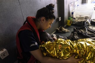 The rescue personnel of the SOS Mediteranee's humanitarian ship Ocean Viking attend migrants rescued from a deflating rubber dinghy in the Central Mediterranean Sea, Wednesday, March 13, 2024. Survivors reported that some 50 people who departed Libya with them a week ago had perished during the journey. (Johanna de Tessieres/ SOS Mediteranee via AP, HO)
