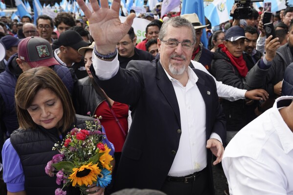 FILE - President-elect Bernardo Arévalo waves as he leads a march in protest of government interference in the elections he won in August, in Guatemala City, Dec. 7, 2023. Arévalo’s imminent Jan. 14th inauguration and the pursuit of him and his party by the attorney general are recurring topics over dinner tables in this country, reflecting a political awakening in a population weary of corruption and impunity. (AP Photo/Moises Castillo, File)
