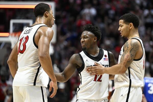 San Diego State forward Jaedon LeDee (13), Darrion Trammell (12) and Matt Bradley celebrate during the second half of the team's NCAA college basketball game against BYU on Friday, Nov. 11, 2022, in San Diego. (AP Photo/Denis Poroy)