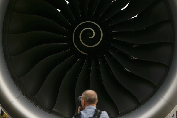 FILE - A visitor takes a photo of the Rolls-Royce jet engine of the Airbus A350-1000 parked at the static display area during the Singapore Airshow on Feb. 7, 2018, in Singapore. Jet engine maker Rolls-Royce said Tuesday Oct. 17, 2023 it's cutting up to 2,500 jobs globally as part of a corporate overhaul that its new CEO is carrying out. (AP Photo/Yong Teck Lim, File)