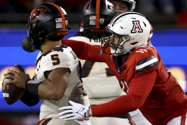 Arizona linebacker Taylor Upshaw (11) sacks Oregon State quarterback DJ Uiagalelei (5) during the second quarter of an NCAA college football game Saturday, Oct. 28, 2023, in Tucson, Ariz. (Kelly Presnell/Arizona Daily Star via AP)