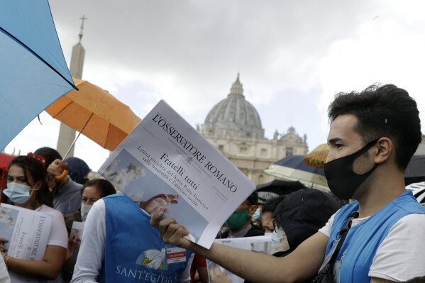 Free copies of the Vatican newspaper L'Osservatore Romano with the front page about Pope Francis' encyclical "All Brothers" are distributed by volunteers to faithful at the end of the Angelus noon prayer in St. Peter's Square at the Vatican, Sunday, Oct. 4, 2020. Francis on Sunday laid out his vision for a post-COVID world by uniting the core elements of his social teachings into a new encyclical, “Fratelli Tutti” (Brothers All), which was released on the feast day of his namesake, the peace-loving St. Francis of Assisi. (AP Photo/Gregorio Borgia)