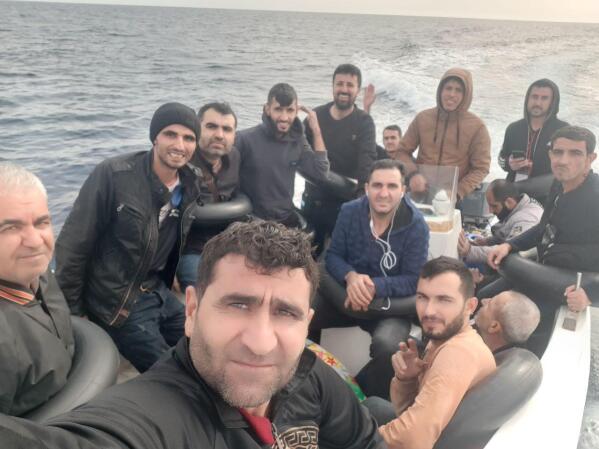 In this UGC photo Baran Mesko takes a selfie in a fishing boat with a dozen other Kurdish Syrian migrants before leaving to Spain in Oran, Algeria, on Saturday, Octo. 15, 2022. A growing number of Syrian Kurds are making the journey to Europe on a circuitous course that includes travel by car and plane across Lebanon, Egypt, Libya, Algeria, then finally by boat to Spain. (AP Photo/Baran Msko)