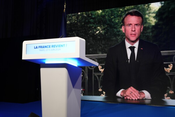 French President Emmanuel Macron appears on television screen at the French far-right National Rally party election night headquarters, Sunday, June 9, 2024 in Paris. (AP Photo/Lewis Joly)