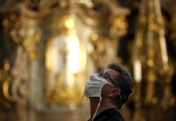A man wearing a face mask visit the St. Nicholas church in Prague, Czech Republic, Thursday, Sept. 10, 2020. The Czech Republic is returning to mandatory mask wearing in interior spaces amid a steep rise in new coronavirus cases. Starting Thursday, people across the country need to cover their face in all public places, including stores, shopping malls, post offices and others but also in private companies where employees cannot keep a distance of 2 meters from one another. (AP Photo/Petr David Josek)