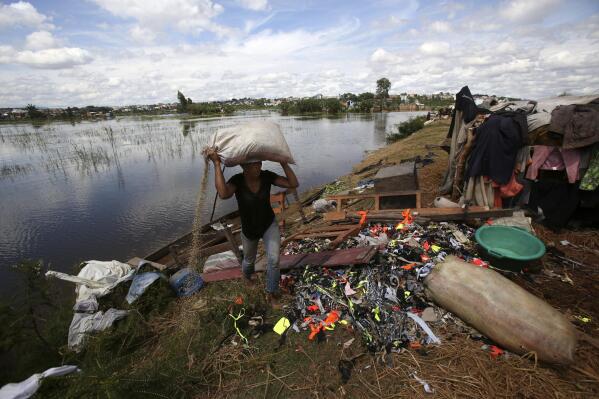 FILE - A man caries belongings from his house destroyed by tropical storm Ana in Antananarivo, Madagascar, Jan. 26, 2022. Extreme rainfall in Africa's southeast has become heavier and more likely to occur during cyclones because of climate change, according to a new analysis released Monday, April 11, 2022 by an international team of weather scientists. (AP Photo/Alexander Joe, file)