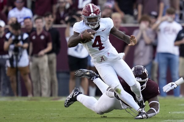 Alabama quarterback Jalen Milroe (4) breaks a tackle attempt by Texas A&M defensive lineman Albert Regis (17) during the second half of an NCAA college football game Saturday, Oct. 7, 2023, in College Station, Texas. (AP Photo/Sam Craft)