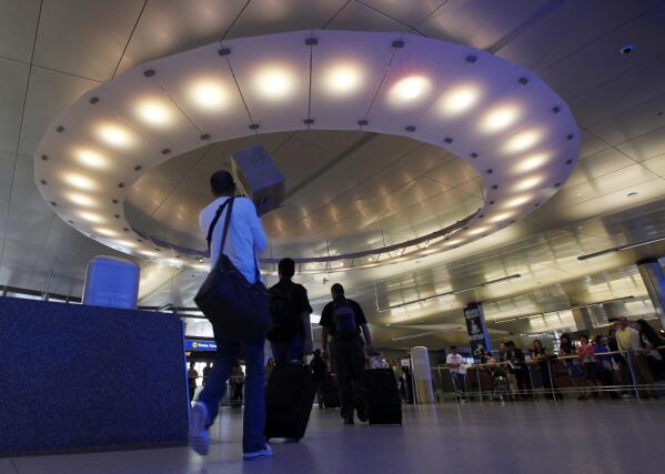 FILE - Arriving international passengers pass under a large "halo" of light in the area where they meet friends and family, at the customs clearance area at the Tom Bradley International Terminal at Los Angeles International Airport, May 28, 2010. Three Muslim Americans have filed a lawsuit alleging that U.S. border officers questioned them about their religious beliefs in violation of their constitutional rights when they returned from international travel. The three men from Minnesota, Texas and Arizona sued Department of Homeland Security officials on Thursday, March 24, 2022, in a federal court in Los Angeles. The suit was filed in California because some of the questioning allegedly occurred at Los Angeles International Airport. (AP Photo/Reed Saxon, File)