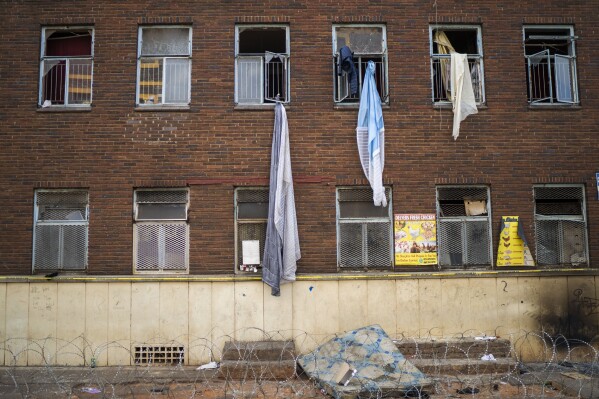 Curtains and sheets used by people trying to flee one of South Africa's deadliest inner-city fires dangle from windows, in Johannesburg, South Africa, Friday, Sept. 1, 2023. Emergency services teams have left the scene of one of South Africa's deadliest inner-city fires as pathologists faced the grisly task Friday of identifying dozens of charred bodies and some separate body parts that had been transported to several mortuaries across the city of Johannesburg. (AP Photo/Jerome Delay)
