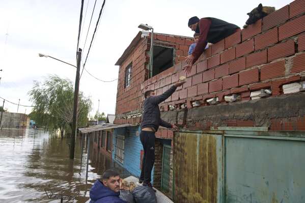A man delivers food to a family whose home was flooded following heavy rains in Campana, Argentina, Saturday, May 17, 2025. (AP Photo/Rodrigo Abd)