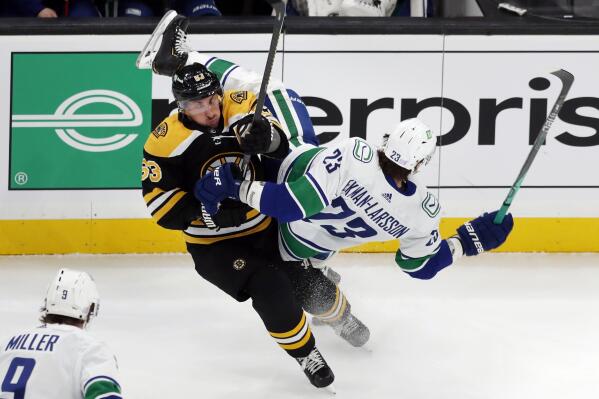 Boston Bruins' Brad Marchand (63) checks Vancouver Canucks' Oliver Ekman-Larsson (23) during the first period of an NHL hockey game, Sunday, Nov. 28, 2021, in Boston. (AP Photo/Michael Dwyer)